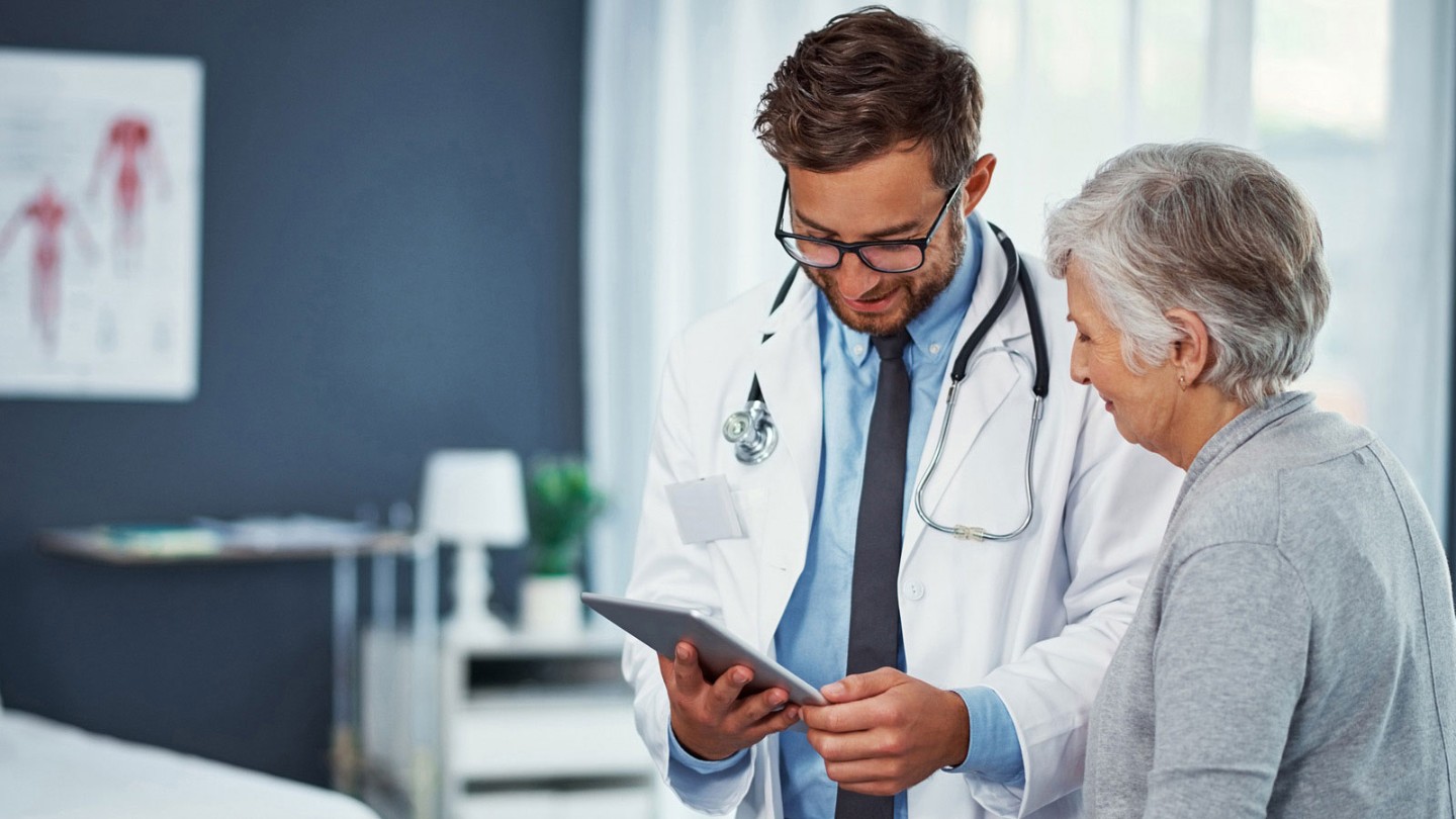 Young physician showing older woman something on tablet